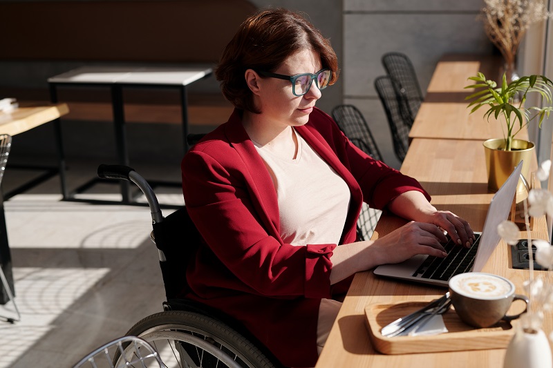 photo of a woman in a wheelchair working on a laptop at a cafe