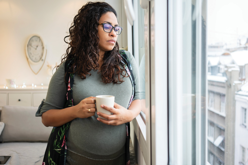 Stock photo of pregnant woman looking out a window