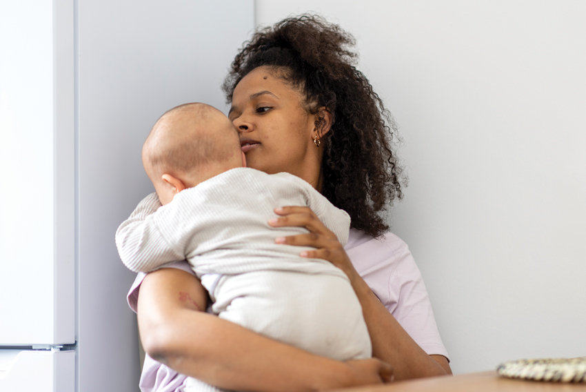 Stock photo of young, frazzled mother holding an infant