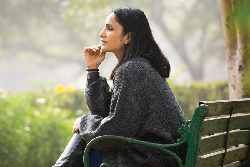 Stock photo of woman in profile sitting on a park bench