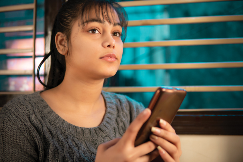 Stock photo of a young woman holding a cell phone in her hand