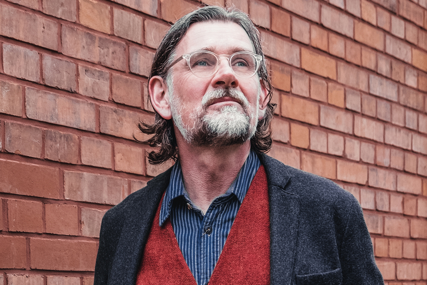 Stock photo of older man standing against a brick wall