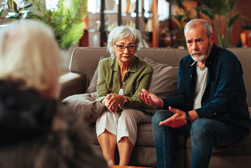 photo of three older people sitting on a couch talking