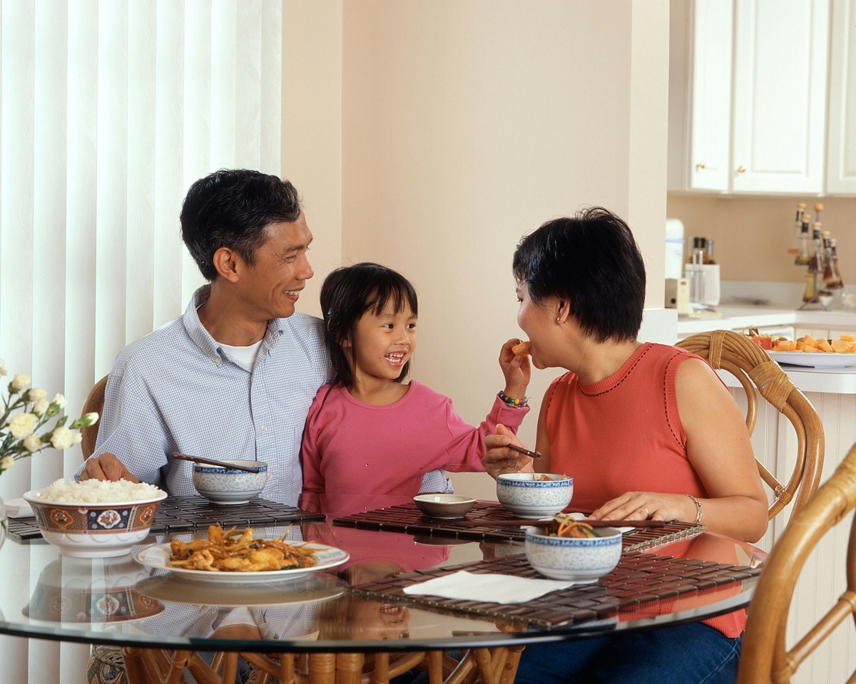 stock photo of two parents eating with a young child